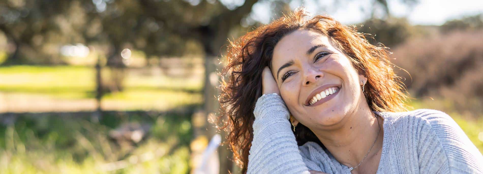 Mujer sonriendo al aire libre, con luz natural